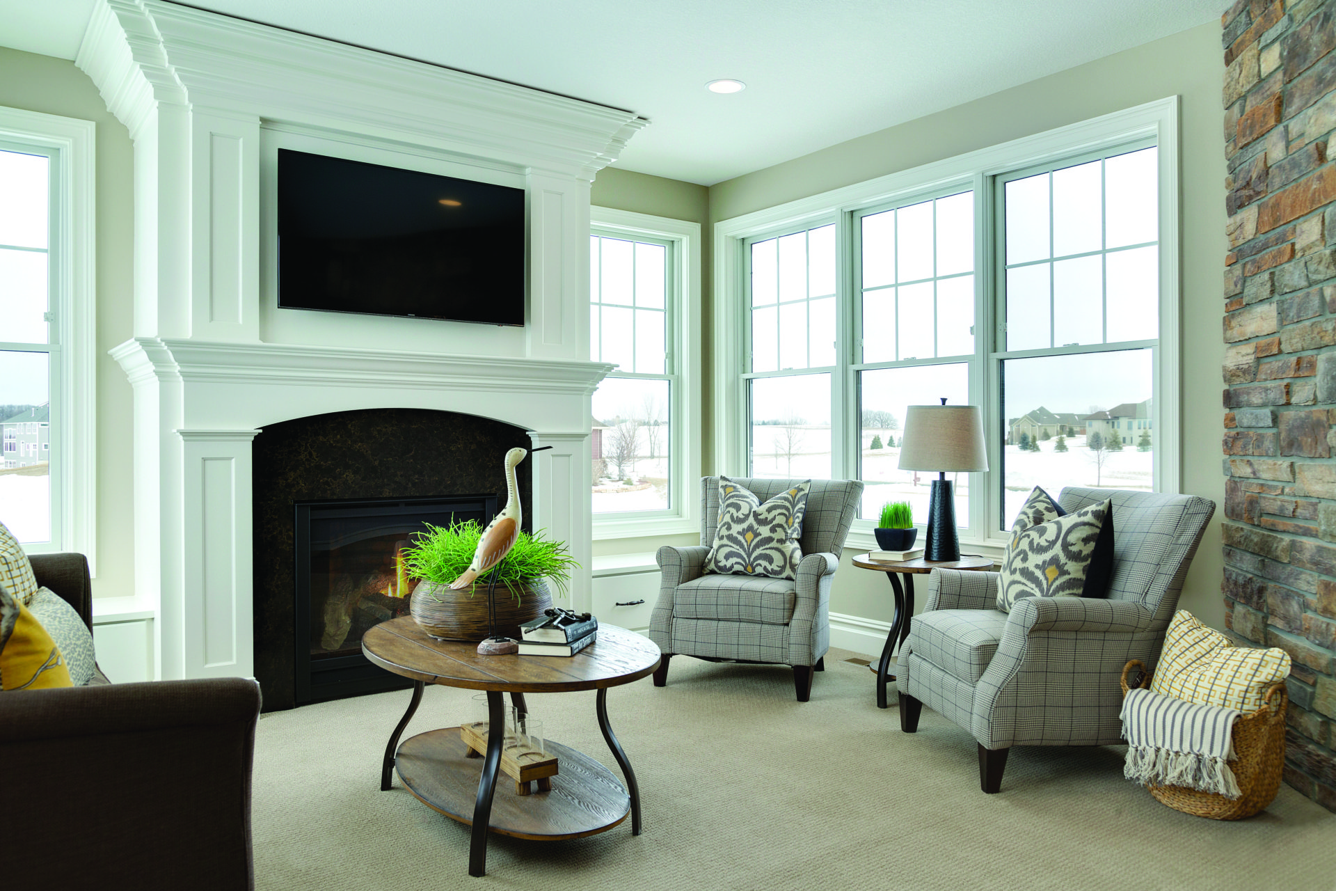 An elegant living room with a large fireplace and Andersen 400 series double hung windows in white