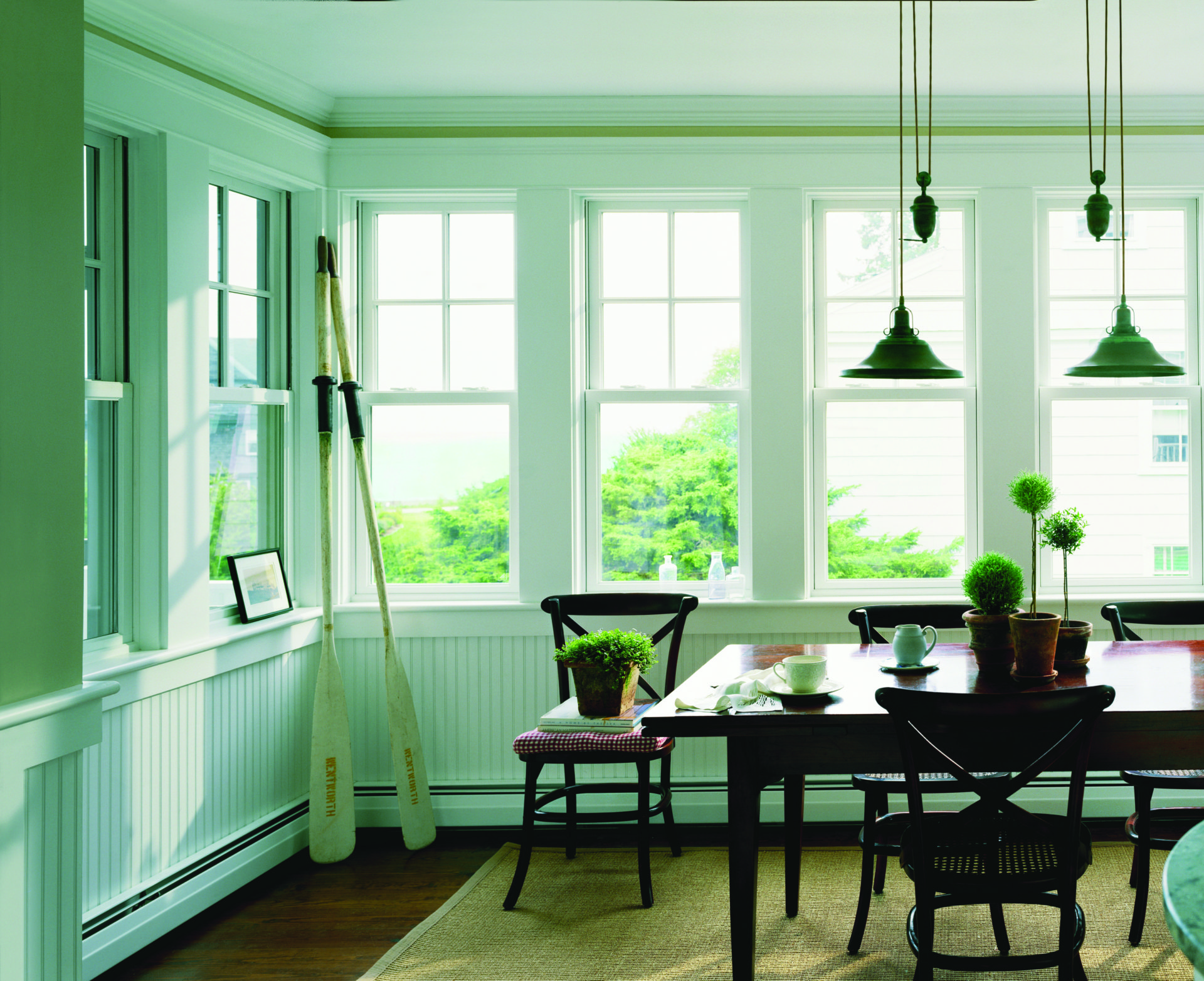 A kitchen nook with a dining table surrounded by eight Andersen 400 Series Woodwright windows