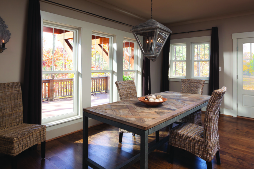 dining room with wood table, white Andersen 100 seris single hung windows overlooking back deck
