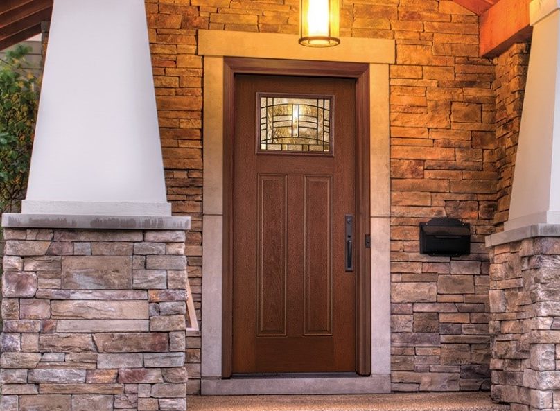 A craftsman style porch with a wood front door