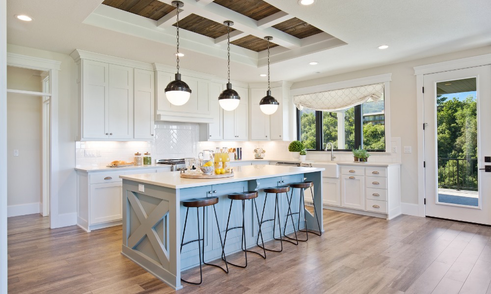 kitchen with a blue island with barstools, modern pendant light fixtures, and a black window overlooking forest view