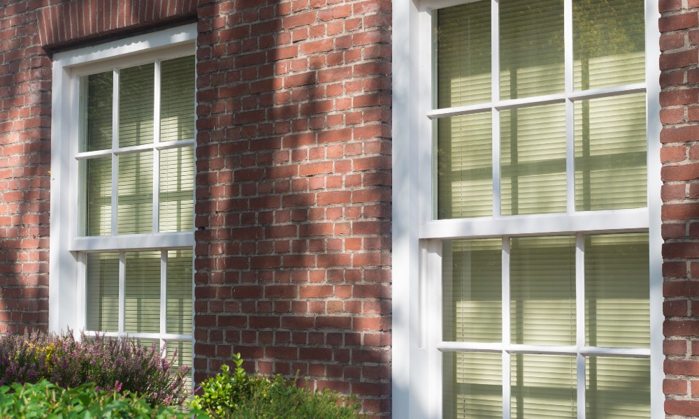 brick home with white double hung windows with six over six grille pattern