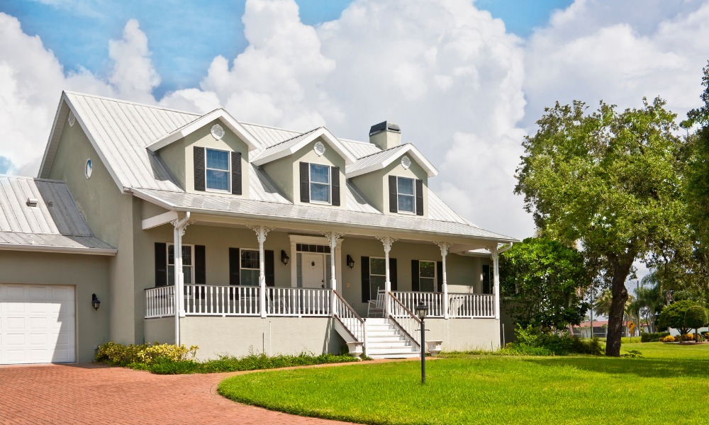 White farmhouse style home with a gabled front porch and three dormer windows