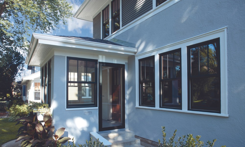 Blue stucco house with black Andersen 400 series woodwrightwindows and white brickmould