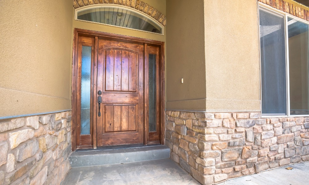 wood front door featuring round transom window and sidelights