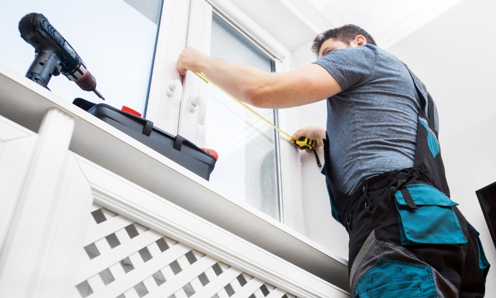 man with construction tools measures a window for replacement window installation
