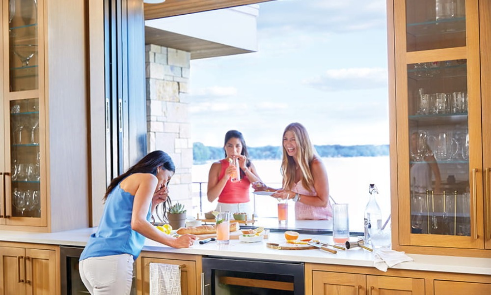 three women share brunch in an indoor outdoor living space created by a kitchen pass-through window