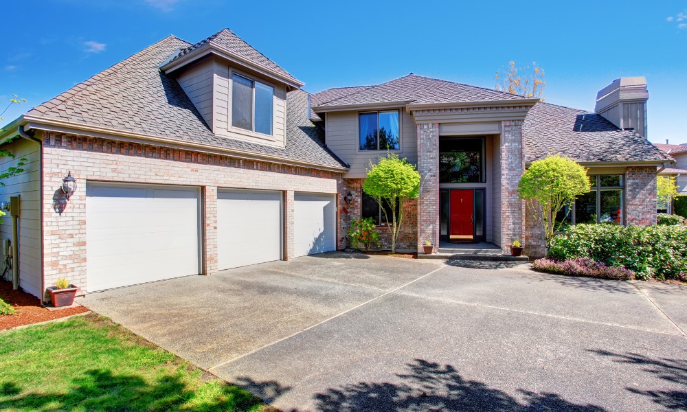 modern Spanish influenced house with three car garage and red front door with a thermal break