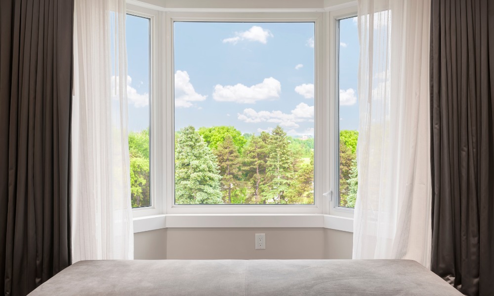 a bay window in a bedroom overlooking a forest