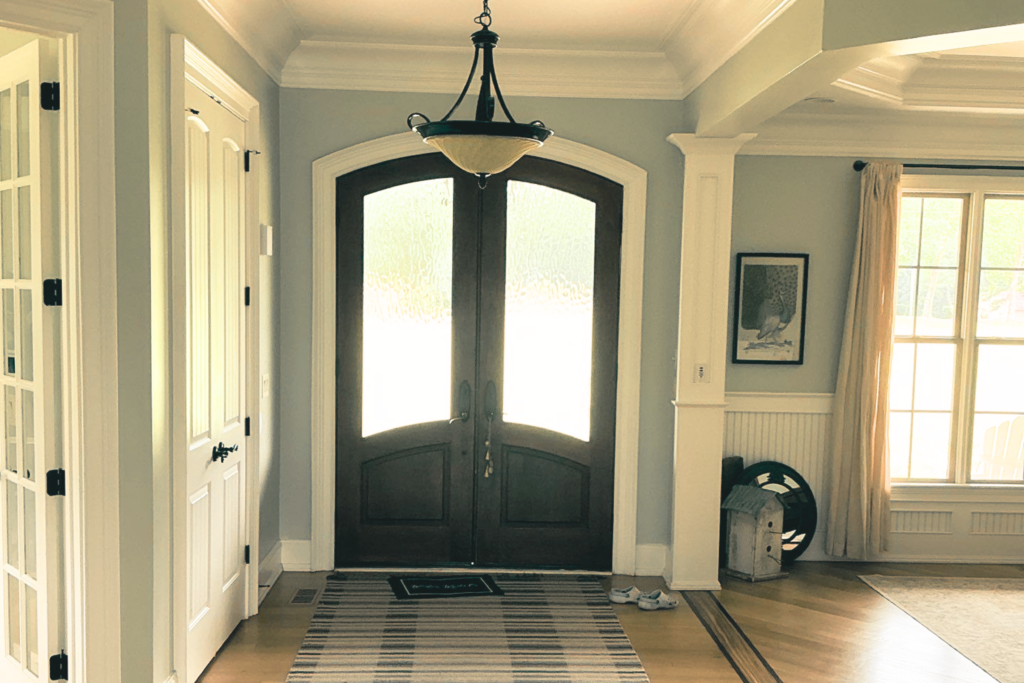An arched wood double door from inside a foyer in a Cary, NC home