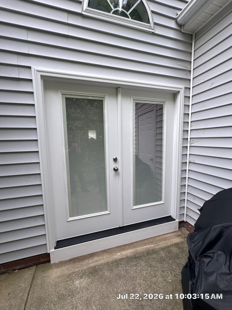 A set of white double doors with large glass panes featuring frosted privacy film is installed in a wall covered with ligh...