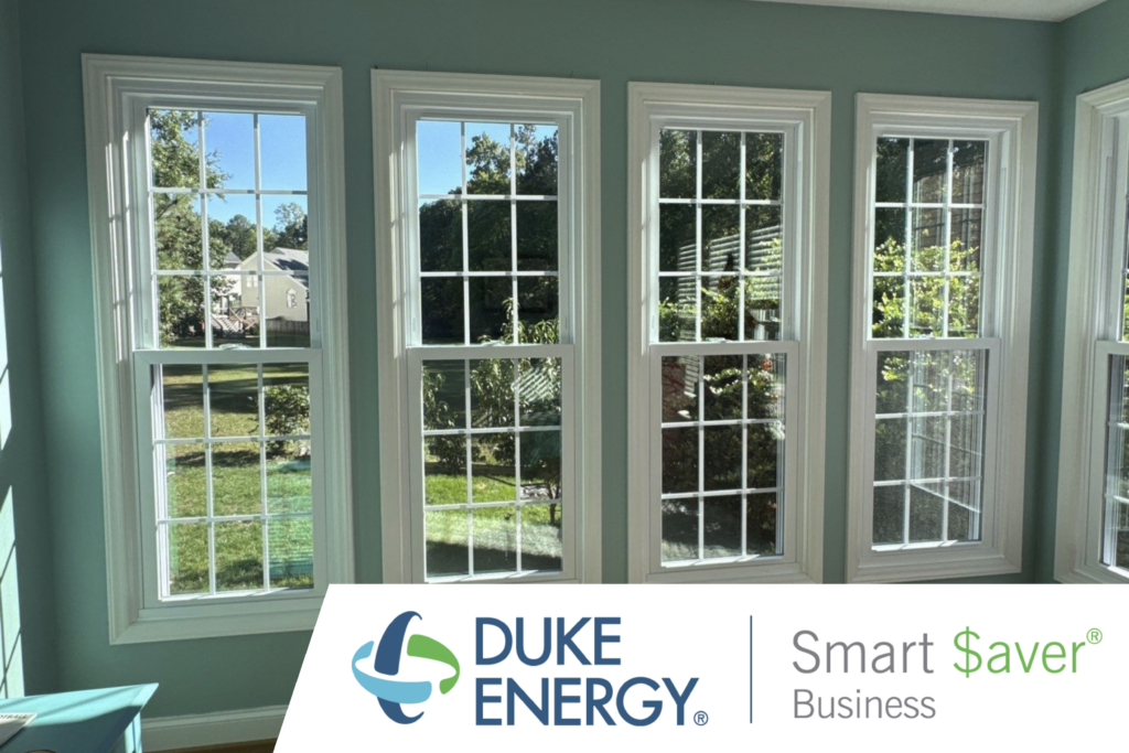 a bank of white double hung replacement windows in a home in Raleigh overlooking a backyard, with the Duke Energy Smart $aver Program logo